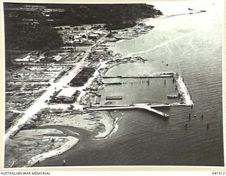 Milne Bay, Papua. 1949-08. Papuan native boys clambering over dumped and wrecked army vehicles being reclaimed by jungle growth. This photograph was taken seven years after World War 2 fighting ..