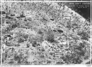 PAPUA, 1943-01-14. THE REMAINS OF BUNA GOVERNMENT STATION, A DESOLATE AREA OF BOMB CRATERS, TWISTED COCONUT TREES, AND THE BURNT AND BLACKENED STUMPS OF GOVERNMENT BUILDINGS, AFTER IT WAS FINALLY ..