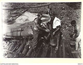 MAPRIK AREA, YAMIL 2, NEW GUINEA. 1945-07-20. PERSONNEL DRAWING WATER FOR A SHOWER FROM A 350-GALLON CANVAS WATER TANK WHICH SUPPLIES WATER TO THE MAIN DRESSING STATION, 2/2 FIELD AMBULANCE AND THE ..