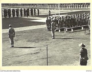 LAE, NEW GUINEA. 1944-04-23. THE AUSTRALIAN GUARD OF HONOUR "PRESENTING ARMS" DURING THE SERVICE AT THE OFFICIAL DEDICATION OF THE LAE WAR CEMETERY. UNITED STATES ARMY REPRESENTATIVES STAND TO ..