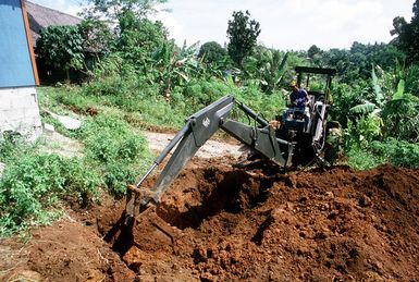 An island resident operates an excavator while working with Seabees from Construction Battalion Unit 3 (CBU-3) on a civic action project at a school