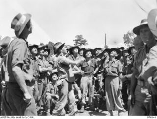 LAE, NEW GUINEA. 1944-11-10. TROOPS OF THE 5TH SUB AREA ENJOY A GAME OF "TWO-UP" ON THE WHARF WHILE AWAITING TO EMBARK ABOARD THE AMERICAN LIBERTY SHIP "J.STERLING MORTON" FOR JACQUINOT BAY