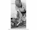 Kelshaw Bonham taking radiation readings from a crab aboard ship, Bikini Atoll, summer 1964