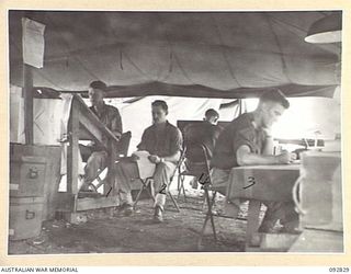 WEWAK AREA, NEW GUINEA. 1945-06-05. MEMBERS OF 3 MOBILE METEOROLOGICAL FLIGHT, RAAF, ATTACHED HEADQUARTERS ROYAL AUSTRALIAN ARTILLERY 6 DIVISION, AT WORK IN THE OFFICE. IDENTIFIED PERSONNEL ARE:- ..