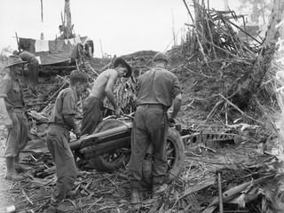 ULUPU, NEW GUINEA, 1945-07-09. MEMBERS OF 2/1 TANK ATTACK REGIMENT, ATTACHED TO 2/5 INFANTRY BATTALION, ASSEMBLING A 75 MM MOUNTAIN GUN AFTER IT HAD BEEN BROUGHT 2 MILES BY NATIVES. WHEN ASSEMBLED ..