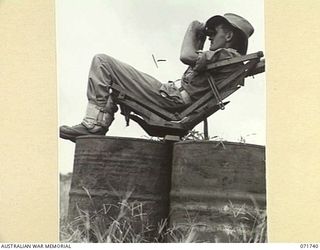 LAE, NEW GUINEA, 1944-03-26. SX17485 GUNNER E. H. MITCHELL, A SPOTTER OF C TROOP, 2/6TH HEAVY ANTI-AIRCRAFT BATTERY CHECKING FOR AIRCRAFT DURING AN ALERT AT THE 2/3RD ANTI-AIRCRAFT REGIMENT ..