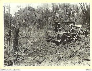 BOUGAINVILLE ISLAND. 1945-02-12. A BULLDOZER OF THE 5TH FIELD COMPANY, BEING USED TO FILL A BOMB CRATER, CAUSED BY THE ROYAL NEW ZEALAND AIR FORCE WHEN THEY WERE BOMBING THE JAPANESE POSITIONS ON ..