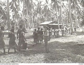 KARKAR ISLAND, NEW GUINEA. 1944-09-19. NX14320 SERGEANT R. DE LEWIS, AUSTRALIAN NEW GUINEA ADMINISTRATIVE UNIT (1), MARCHING NATIVES TO WORK AT NEARBY PLANTATIONS