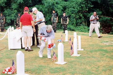 During the 50th anniversary ceremony of the World War II Liberation of Guam, former handlers of war dogs place flowers on the graves of comrades who gave their lives to save others