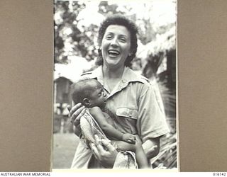 NEW GUINEA. 1943-11-17. PORTRAIT OF MEMBER OF THE AUSTRALIAN ARMY MEDICAL WOMEN'S SERVICE (AAMWS) JEANNINE LEWIS OF POTTS POINT, NSW, WHO IS NOT DOING SO WELL WITH 2 MONTHS OLD PAPUAN BABY, MARAGI. ..