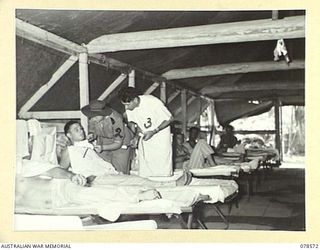 BOUGAINVILLE ISLAND. 1945-01-23. SFX3062 SISTER ELIZABETH IRENE UREN, AUSTRALIAN ARMY NURSING SERVICE (2) ASSISTED BY NX132074 PRIVATE HARVEY, MEDICAL ORDERLY (3), ATTENDING TO PATIENTS IN ONE OF ..