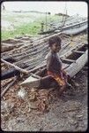 Canoes: Child sits on fishing canoe, other canoes in background at Wawela village