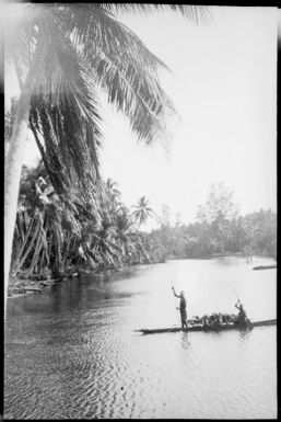 Two people in a laden canoe approaching a village, Ramu River, New Guinea, 1935 / Sarah Chinnery