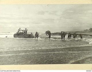 DRINIUMOR RIVER, NEW GUINEA. 1944-11-09. TROOPS OF 2/10 COMMANDO SQUADRON WADING ASHORE FROM AN AMPHIBIOUS DUKW STRANDED AT DRINIUMOR RIVER DURING THEIR JOURNEY TO BABIANG
