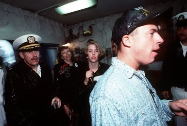 The commanding officer of the amphibious assault ship USS GUAM (LPH-9), left, and his family come in out of the rain following the ship's arrival at the naval station. The GUAM has returned to Norfolk after its deployment to the Persian Gulf region for Operation Desert Shield and Operation Desert Storm