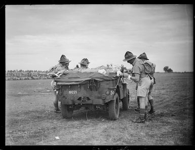 Soldiers lashing ropes to the back of a jeep