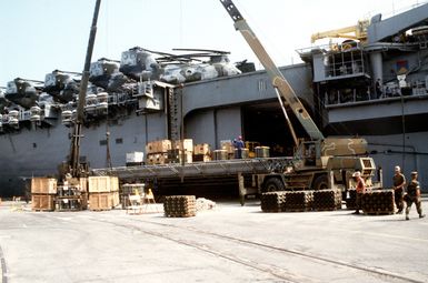 CH-53 Sea Knight helicopters line the deck of the amphibious assault ship USS GUAM (LPH-9) as equipment and ordnance are placed in the vessel's cargo hold for transportation to Saudi Arabia in support of Operation Desert Shield