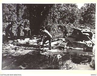 SOUTH BOUGAINVILLE. 1945-07-24. TROOPS OF 2/4 ARMOURED REGIMENT CONSTRUCTING A TEMPORARY BRIDGE OVER A ROAD WASHAWAY ON THE BUIN ROAD, EAST OF THE OGORATA RIVER. THE MATILDA TANK, "BULLECOURT", AT ..