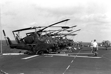 Eight Marine AH-1 Sea Cobra helicopters and UH-1N Iroquois helicopters are tied down on the flight deck of the amphibious assault ship USS GUAM (LPH-9). The helicopters will be used in support of the 1ST Battalion, 6th Marines, cold weather training