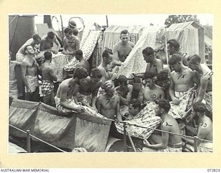 MADANG, NEW GUINEA, 1944-04-30. PERSONNEL FROM HMA MOTOR LAUNCH 816 AND 242 ABOARD HMA MOTOR LAUNCH 424 EXCHANGING BRIGHTLY COLOURED JAPANESE CLOTH FOUND AT MADANG. IDENTIFIED PERSONNEL ARE:- ABLE ..