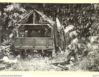 YAULA, NEW GUINEA. 1944-04-09. A MEMBER OF THE 57/60TH INFANTRY BATTALION VIEWING ONE OF THE MANY JAPANESE TRUCKS CAPTURED BY THE UNIT ON THE ROAD TO BOGADJIM