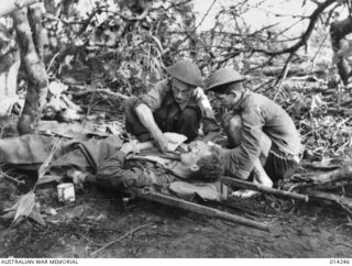 1943-01-27. PAPUA. SANANANDA AREA. A REGIMENTAL BASE AT SANANANDA BEACH. THE MEDICAL OFFICER CAPTAIN C. COPLAND OF MELBOURNE DRESSES THE WOUND OF AN AUSTRALIAN SHOT IN THE ARM. HE HAD BEEN WOUNDED ..