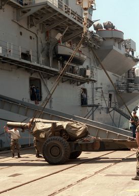 Marines load a Howitzer aboard the amphibious assault ship USS GUAM (LPH 9) during Exercise SOLID SHIELD '87