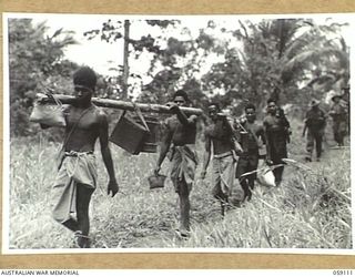Bukaua (Bukawa), New Guinea, 1943-10-18. Native carriers of the 29/46th Australian Infantry Battalion transporting loads of rations and ammunition. Leading the carriers is Kepigeya of Buingim