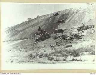 Rouna, New Guinea. 1944-01-11. A hillside in the vicinity of Ward's Airfield being quarried for road surfacing material. A bulldozer pushes the material down to a mechanical shovel which loads it ..