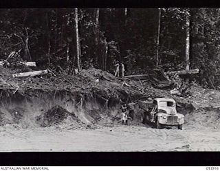 REINHOLD HIGHWAY, NEW GUINEA. 1943-07-08. NATIVES AND HQ ROYAL AUSTRALIAN ENGINEERS OF 11TH AUSTRALIAN DIVISION LOADING TRUCK WITH SAND FOR THE ROAD AFTER BULLDOZERS HAVE CLEARED AWAY OVERBURDEN