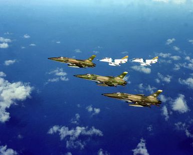An air-to-air left side view of three F-105 Thunderchief aircraft from 508th Tactical Air Force Reserve Unit and two TA-4J Skyhawk aircraft from Fleet Composite Squadron 1 (VC-1) flying in formation
