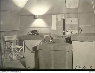 MADANG, NEW GUINEA. C. 1944-10. INTERIOR OF THE STUDIO OF RAAF RADIO STATION "THE VOICE OF THE ISLANDS". IN THE FOREGROUND IS THE CONTROL DESK