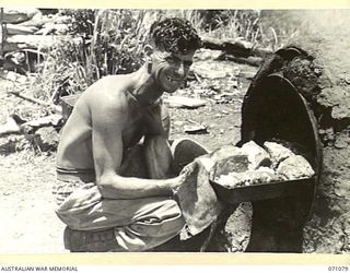 EVAPIA RIVER, NEW GUINEA. 1944-03-15. VX85760 PRIVATE H.A. WALBRIDGE, THE COOK OF NO. 2 PLATOON, 2/4TH FIELD COMPANY, PREPARING A ROAST FOR THE TROOPS