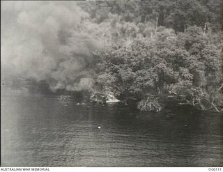 OFF NEW BRITAIN ISLAND, NEW GUINEA. C. 1943-10. SMOKE POURING FROM A BURNING BARGE AFTER IT HAD BEEN STRAFED BY BEAUFIGHTER AIRCRAFT OF NO. 30 SQUADRON RAAF IN A SWEEP ALONG THE NORTH COAST OF NEW ..