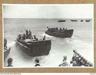 KANOMI BEACH, NEW GUINEA. 1944-01-05. TROOPS OF THE 2/23RD AUSTRALIAN INFANTRY BATTALION, 26TH AUSTRALIAN INFANTRY BRIGADE, 9TH AUSTRALIAN DIVISION ABOARD BARGES WHICH ARE TO TAKE THEM UP THE COAST ..