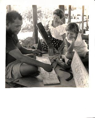 Photo of 'Sebal. Hamlet of Koror, Palau District, Western Caroline Islands. Carver specialises in painted carved story boards'.