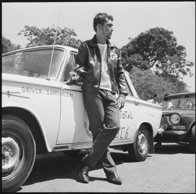 Rally driver G. Bart Helemy leaning on his rally car during the 1st Safari Calédonien racing event, New Caledonia, 1967 / Michael Terry