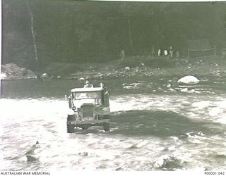 THE SOLOMON ISLANDS, 1945-01-12. AIF PERSONNEL AND TRUCK CROSSING A RIVER. THEIR CAMPSITE CAN BE SEEN ON THE FAR SIDE OF THE RIVER. (RNZAF OFFICIAL PHOTOGRAPH.)