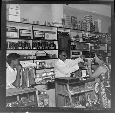 Unidentified Indian man and boy serving in a shop, Nadi, Fiji