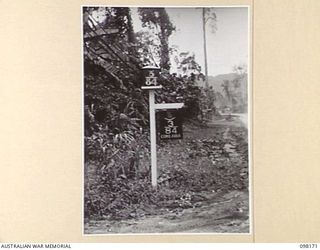 TOROKINA, BOUGAINVILLE. 1945-10-20. THE ENTRANCE TO HEADQUARTERS 3 DIVISION, SHOWING THE 3 DIVISION FORMATION SIGN OF THE KOALA OVER THE BOOMERANG