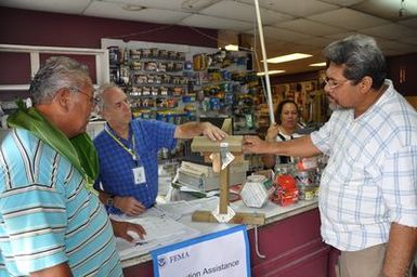 Tafuna, American Samoa, December 14, 2009 -- David Kulberg, FEMA Mitigation Specialist, explains "continuous load path" construction technique to build strong, earthquake and wind-resistant dwellings. Anufe Lavatai, right, and Faitio Faatea, left, customers of C. B. T. Ho Ching & Co. , listen while cashier Tulai Lilomaiava looks on. FEMA/Richard O'Reilly.