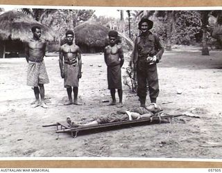 KAIAPIT, NEW GUINEA, 1943-09-22. SX1165 CORPORAL J.A. WILSON MM, 2/6TH AUSTRALIAN INDEPENDENT COMPANY, IN THE VILLAGE WITH THREE NATIVE CARRIERS AND A WOUNDED JAPANESE SOLDIER LYING ON A STRETCHER, ..