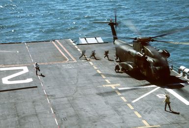 Marines cross the deck of the amphibious assault ship USS SAIPAN (LHA-2) to board a Marine CH-53 Sea Stallion helicopter