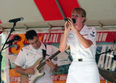 US Navy (USN) Musician Second Class (MU2) Mallory McKendry sings to an audience as USN MU2 Brain Nefferdorf plays the guitar during a public concert at the Pearl Harbor Navy Exchange mall