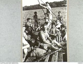PAPUA, NEW GUINEA. 1942-07. AUSTRALIAN INFANTRYMEN ON PATROL CROSSING A RIVER ABOARD A NATIVE "LAKATOI" MANNED BY FIVE SMALL PAPUAN BOYS. NOTICE THAT ONLY ONE OF THE HIRED CREW IS WORKING - THE ..