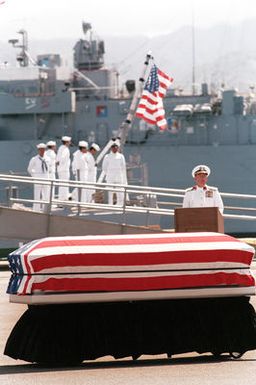 Admiral Sylvester R. Foley Jr., commander in chief, US Pacific Fleet, speaks during the designation and departure ceremony for the Unknown Serviceman of the Vietnam Era. The Unknown's flag-draped casket is in the foreground. At the conclusion of the ceremony, the Unknown will be placed aboard the USS BREWTON (FF 1086) for transport to Naval Air Station, Alameda, California