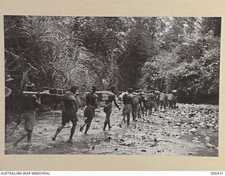 WONGINARA MISSION, NEW GUINEA. 1945-04-04. NATIVES CARRYING SUPPLIES ALONG A KAI (FOOD) LINE ALONG THE MABAM RIVER TO FORWARD 2/3 INFANTRY BATTALION TROOPS IN THE TORRICELLI MOUNTAINS. THE LINE WAS ..