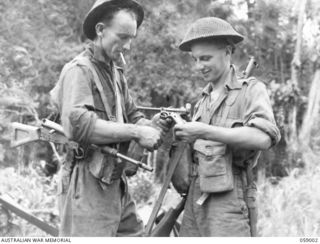 DUMPU, NEW GUINEA. 1943-10-15. SX12508 CORPORAL P. J. CAREY (LEFT) AND SX17771 PRIVATE C. R. FISHER OF NO. 7 PLATOON, "A" COMPANY, 2/27TH AUSTRALIAN INFANTRY BATTALION EXAMINING A JAPANESE PISTOL ..