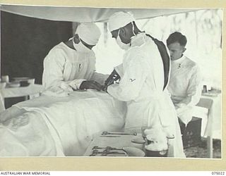 NAGADA, NEW GUINEA. 1944-08-02. THE SURGEON AND HIS ASSISTANTS AT WORK IN THE OPERATING THEATRE OF THE 4TH FIELD AMBULANCE. IDENTIFIED PERSONNEL ARE:- VX106539 SERGEANT L. MCMURRAY (1); WX3324 ..