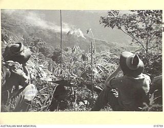 1943-09-20. NEW GUINEA. ROOSEVELT RIDGE. TWO AUSTRALIAN SOLDIERS WATCH THE RESULT OF SMOKE SHELLS FINDING THE RANGE ON ROOSEVELT RIDGE. (NEGATIVE BY W. CARTY)